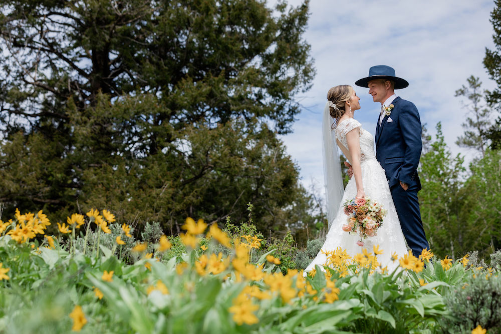 A couple stands in a field of wildflowers in Jackson Hole. Photo by Wyoming wedding photographer Jamye Chrisman
